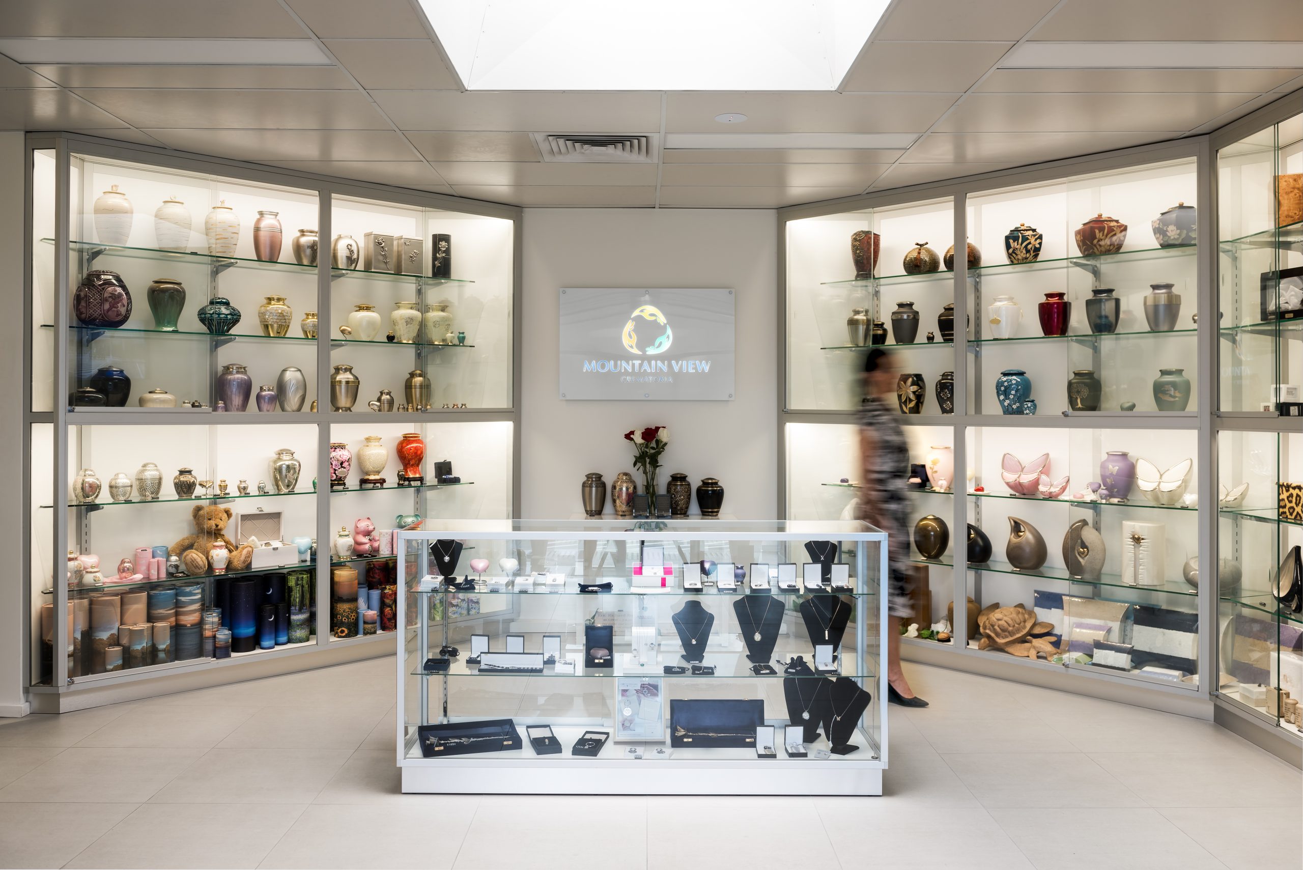 Funeral showroom displaying a range of urns, memorial jewellery and keepsake items in glass display cabinets.