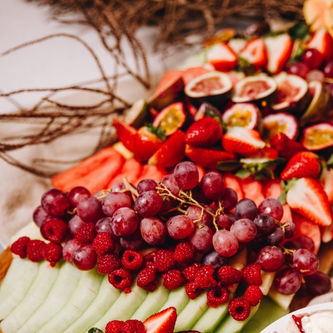 Colourful fruit platter with strawberries, grapes, raspberries, melon and passionfruit.